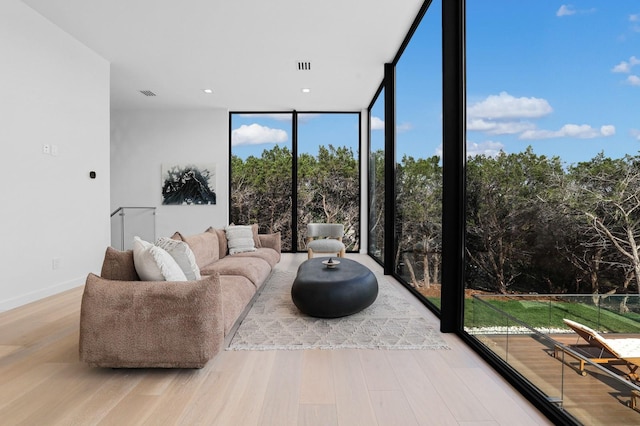 living room featuring baseboards, wood finished floors, visible vents, and floor to ceiling windows