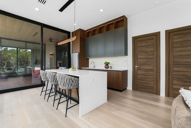 kitchen featuring light wood-style floors, tasteful backsplash, modern cabinets, and floor to ceiling windows