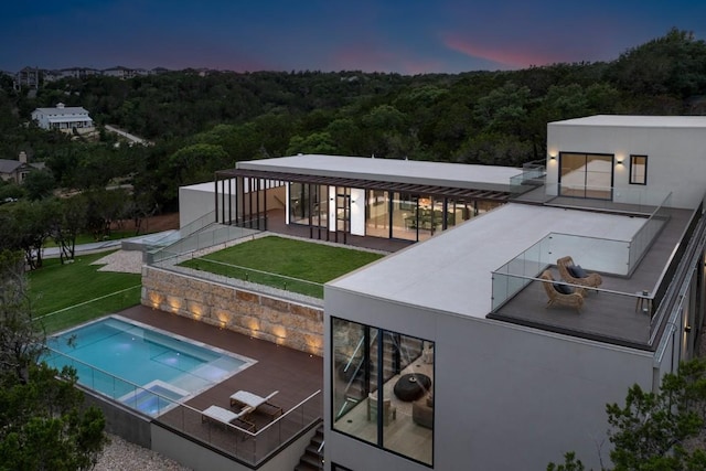 pool at dusk featuring a lawn and a patio area