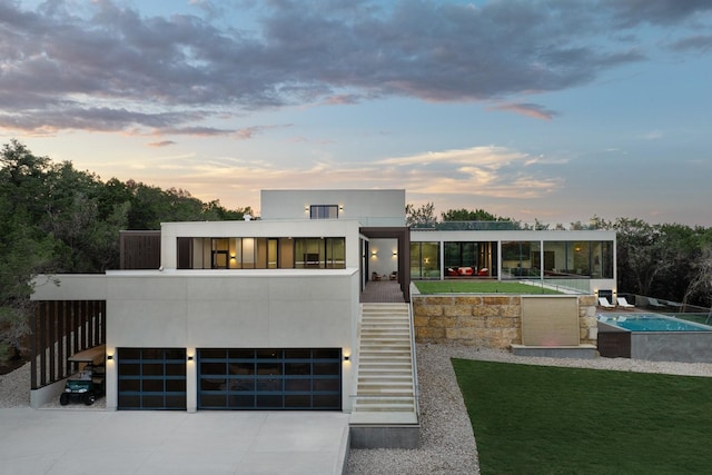 contemporary house with a fenced in pool, stucco siding, stairway, a garage, and driveway