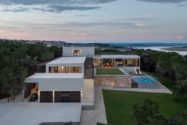 back house at dusk featuring a water view and a yard