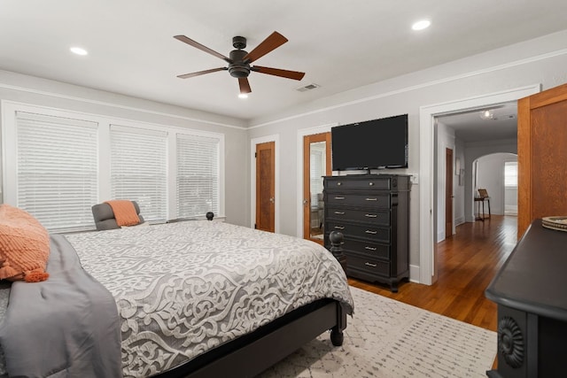 bedroom with arched walkways, dark wood-style floors, visible vents, and recessed lighting