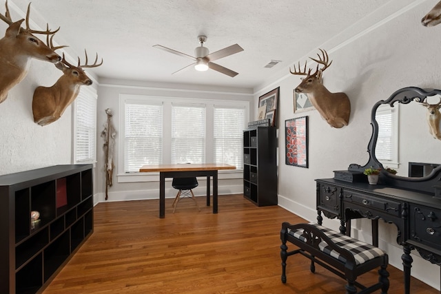 office space with baseboards, visible vents, a ceiling fan, wood finished floors, and a textured ceiling