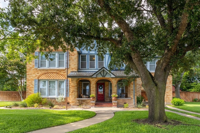 view of front of home with a front yard, brick siding, and fence