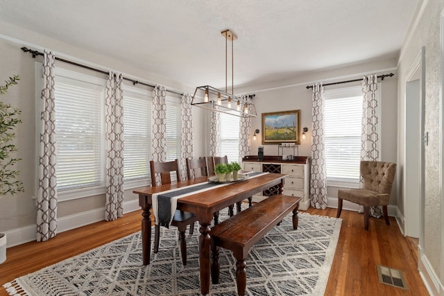 dining space featuring wood finished floors, visible vents, and baseboards