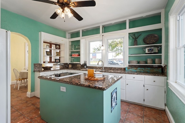 kitchen featuring arched walkways, open shelves, white cabinets, and a center island