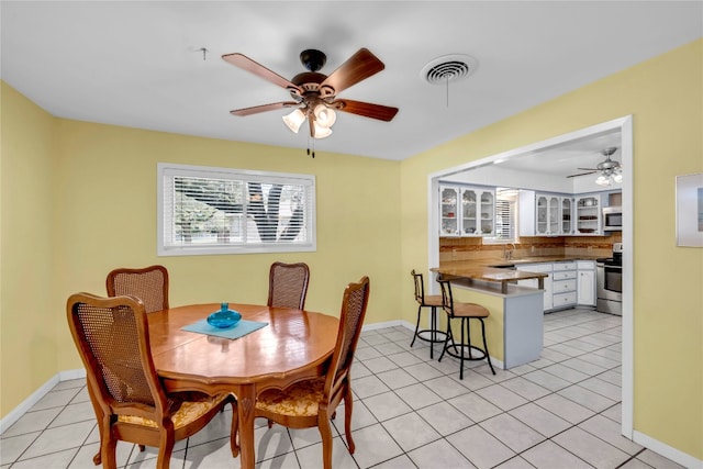 tiled dining room featuring ceiling fan and sink