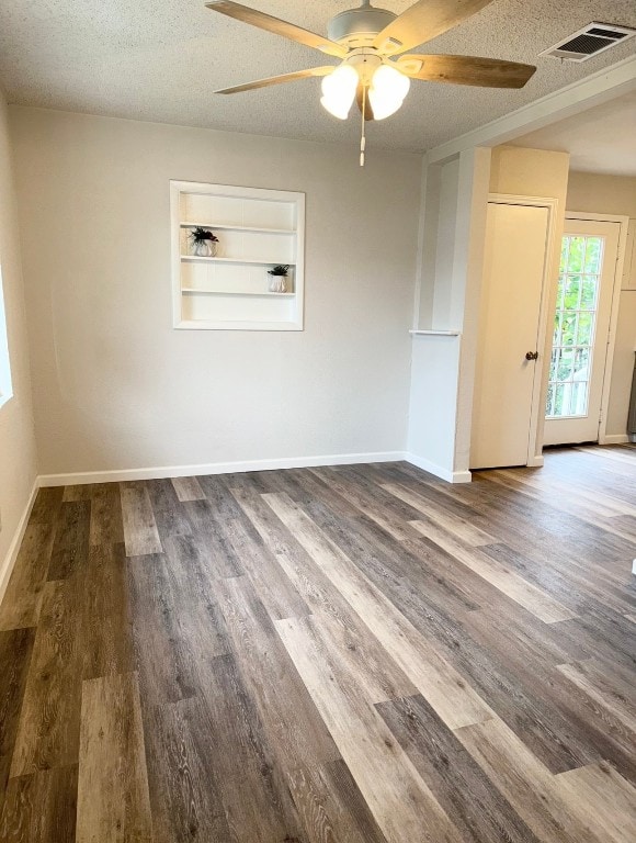 unfurnished room with hardwood / wood-style floors, a textured ceiling, built in features, and ceiling fan