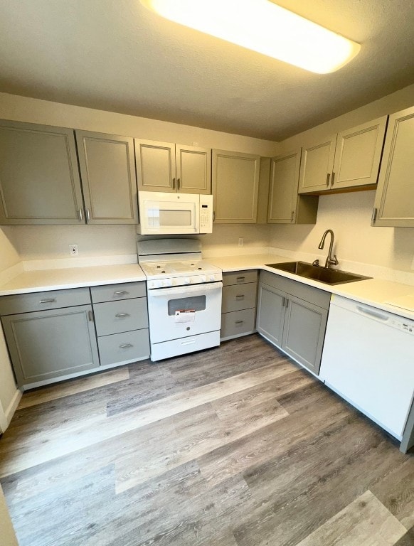 kitchen with gray cabinets, light hardwood / wood-style floors, white appliances, and sink