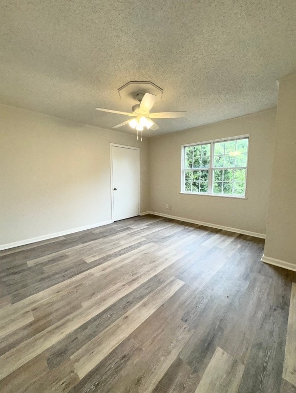 empty room with hardwood / wood-style floors, ceiling fan, and a textured ceiling