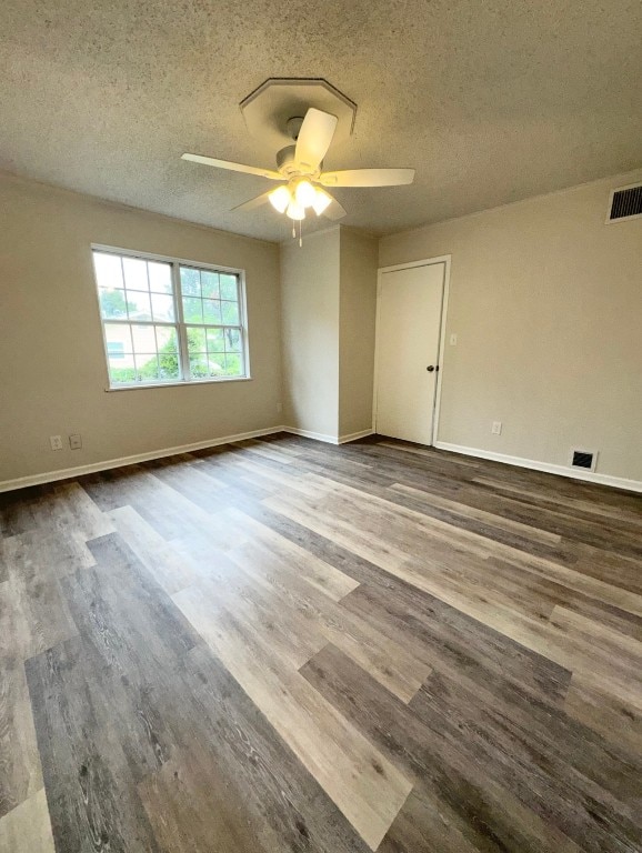 empty room with ceiling fan, wood-type flooring, and a textured ceiling