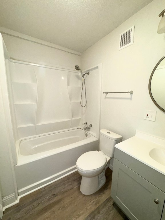 full bathroom featuring hardwood / wood-style floors, a textured ceiling, toilet, vanity, and shower / bathtub combination