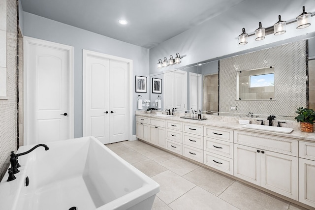 bathroom featuring tile patterned floors, a freestanding bath, double vanity, and a sink