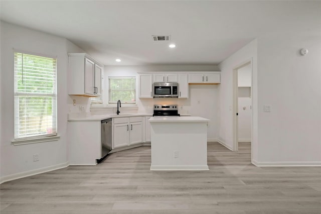 kitchen with white cabinets, a kitchen island, sink, and stainless steel appliances