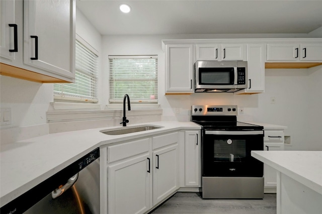 kitchen with white cabinets, sink, light wood-type flooring, and stainless steel appliances