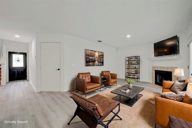 living room with a tiled fireplace and light hardwood / wood-style flooring