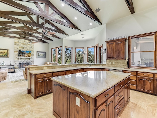 kitchen with beamed ceiling, a kitchen island, hanging light fixtures, and a fireplace