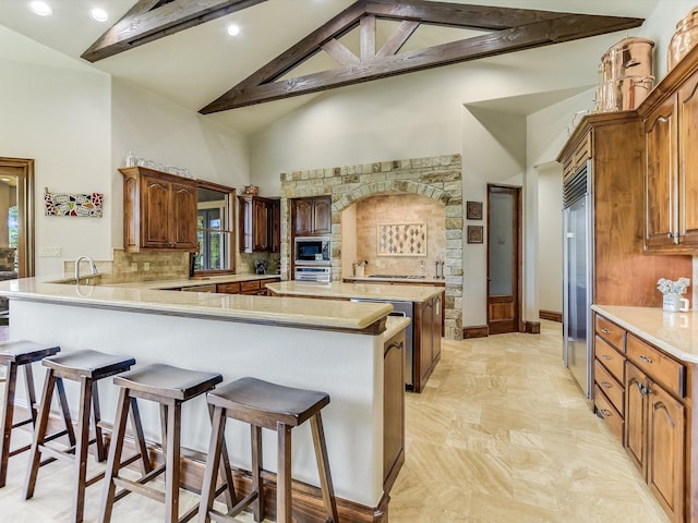 kitchen with high vaulted ceiling, decorative backsplash, built in appliances, kitchen peninsula, and beam ceiling