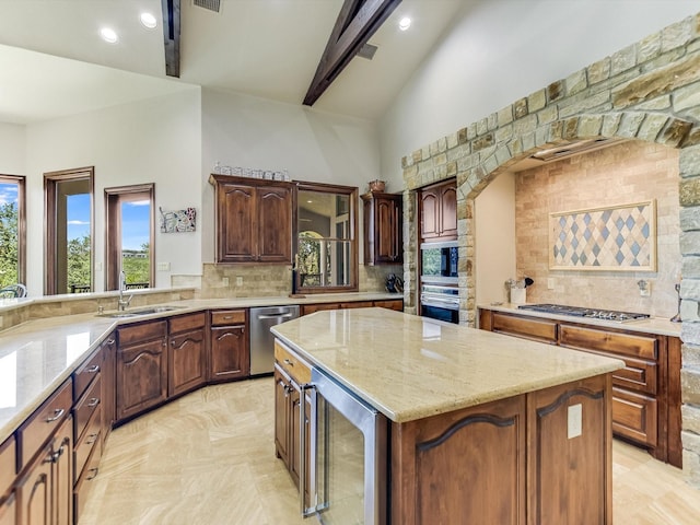 kitchen featuring sink, appliances with stainless steel finishes, beverage cooler, a kitchen island, and beam ceiling