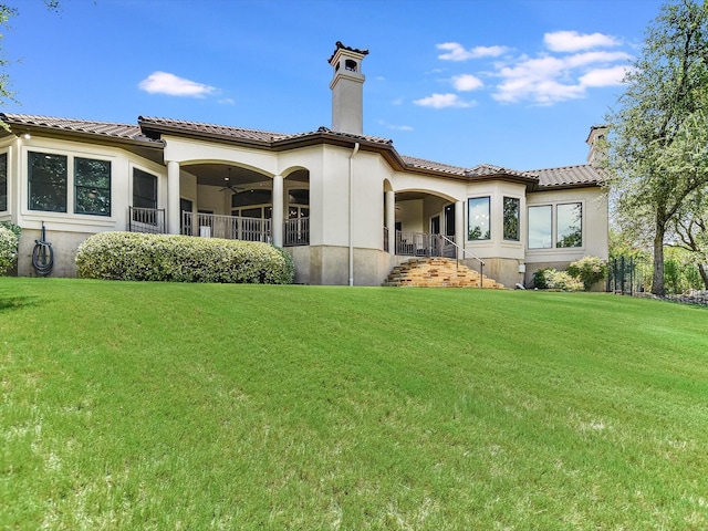 back of house with ceiling fan and a lawn