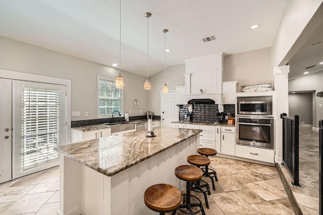 kitchen featuring visible vents, a sink, stainless steel appliances, white cabinetry, and tasteful backsplash