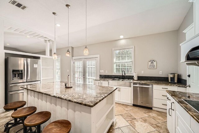 7507 Davy Dr, Volente, TX 78641 - kitchen with stainless steel appliances, dark stone counters, white cabinetry, a kitchen bar, and a center island