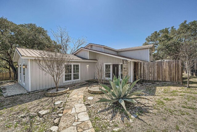 back of property with metal roof, a standing seam roof, and fence