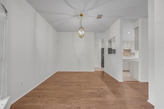 unfurnished dining area featuring light wood-type flooring and an inviting chandelier