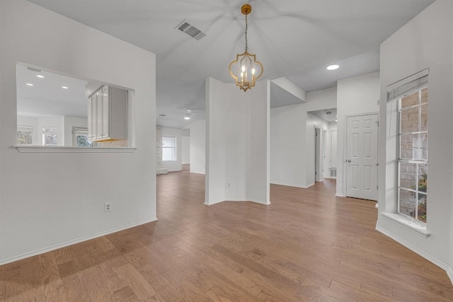 unfurnished room with plenty of natural light, light hardwood / wood-style floors, and a notable chandelier