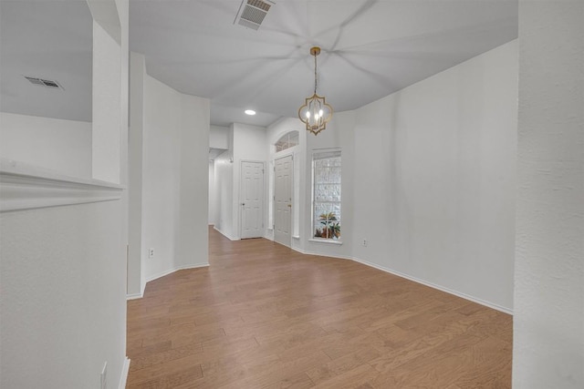 unfurnished dining area featuring an inviting chandelier and light hardwood / wood-style flooring