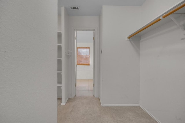 walk in closet featuring light colored carpet