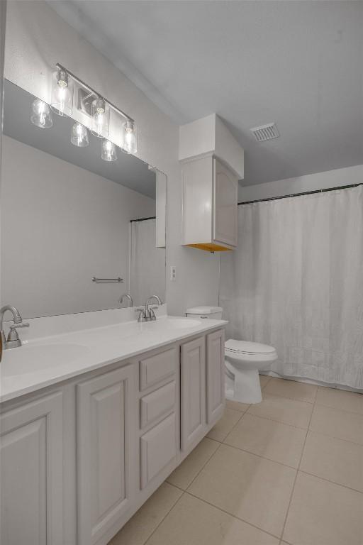 bathroom featuring toilet, vanity, and tile patterned floors