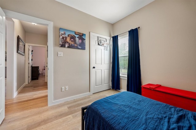 bedroom with light wood-style flooring and baseboards