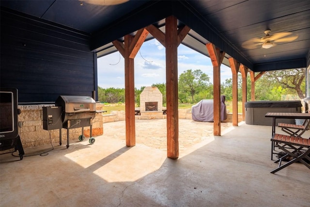 view of patio with ceiling fan, an outdoor kitchen, an outdoor stone fireplace, grilling area, and a hot tub