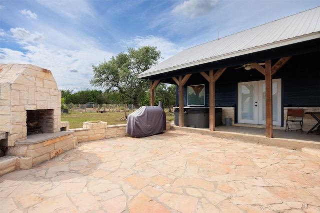 view of patio / terrace with a ceiling fan, an outdoor stone fireplace, a grill, and french doors