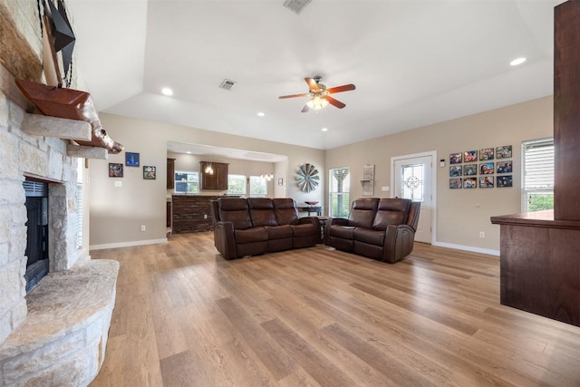 living room featuring light wood-type flooring, visible vents, a fireplace, and baseboards