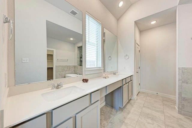 full bath featuring double vanity, visible vents, a sink, and a bath