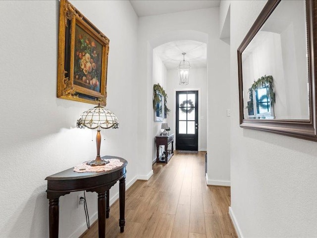 entryway featuring arched walkways, wood finished floors, and baseboards