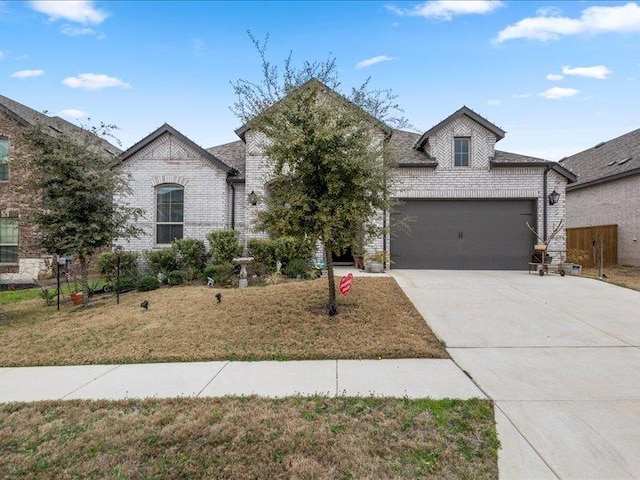 view of front facade with a garage, driveway, brick siding, and a front yard