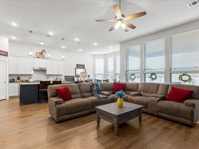 living area with light wood-style flooring, a ceiling fan, visible vents, and recessed lighting