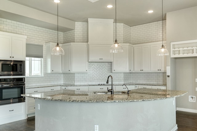 kitchen featuring sink, a kitchen island with sink, hanging light fixtures, stainless steel appliances, and white cabinets