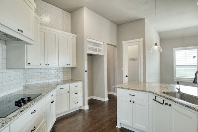 kitchen featuring white cabinetry, sink, black electric stovetop, and decorative light fixtures