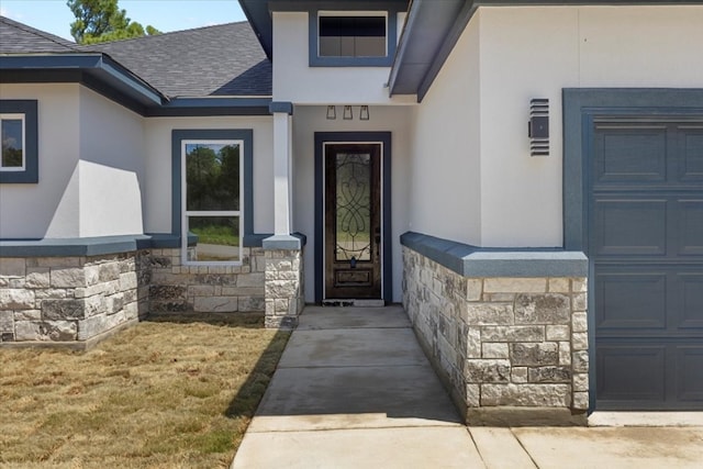 entrance to property featuring a yard and a garage