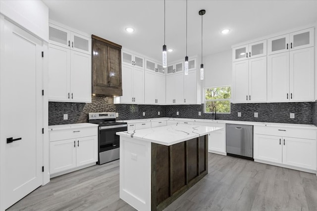 kitchen with white cabinets, a center island, light stone counters, and stainless steel appliances