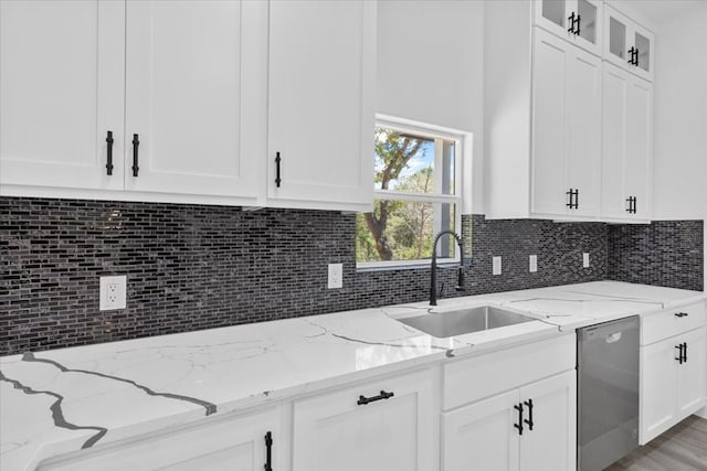 kitchen with dishwasher, white cabinetry, sink, and light stone countertops