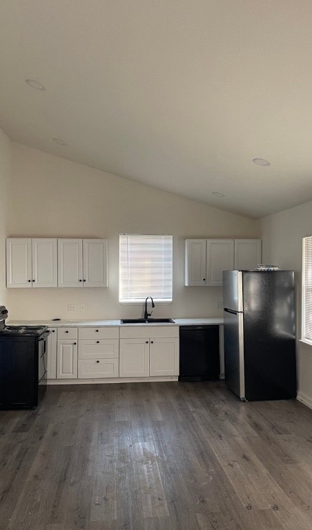 kitchen featuring stainless steel fridge, white cabinetry, lofted ceiling, dishwasher, and electric range