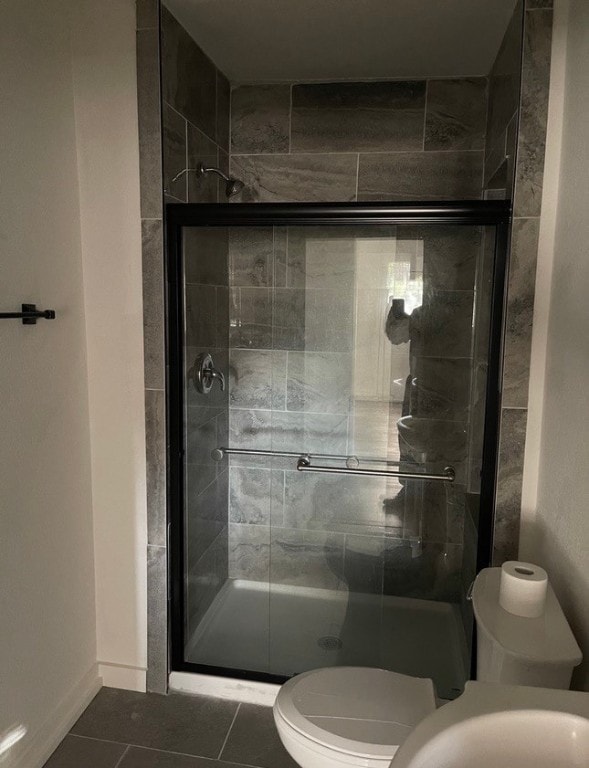 bathroom with tile patterned floors, toilet, and an enclosed shower