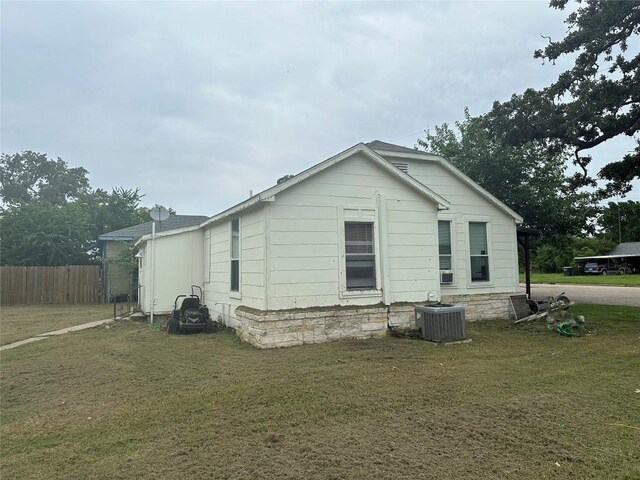 view of side of home with central AC and a yard