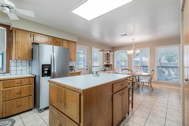 kitchen featuring light tile patterned flooring, pendant lighting, decorative backsplash, a center island, and stainless steel refrigerator with ice dispenser