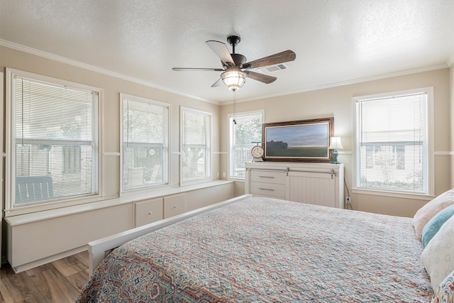 bedroom with hardwood / wood-style flooring, ornamental molding, ceiling fan, and a textured ceiling